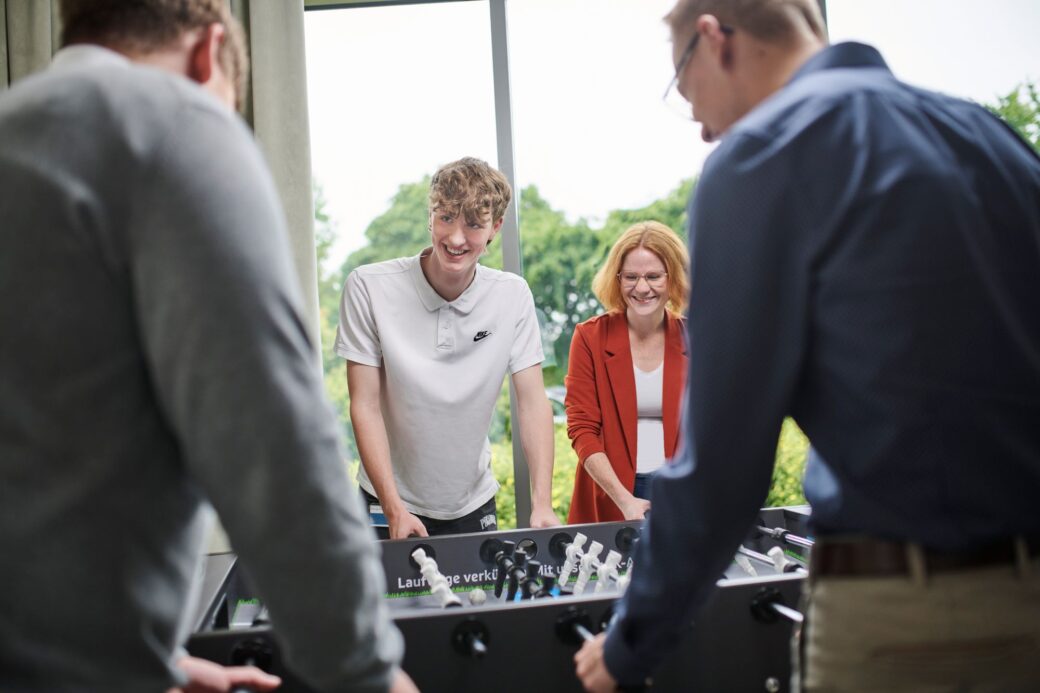 Mitarbeitende spielen gemeinsam am Kickertisch